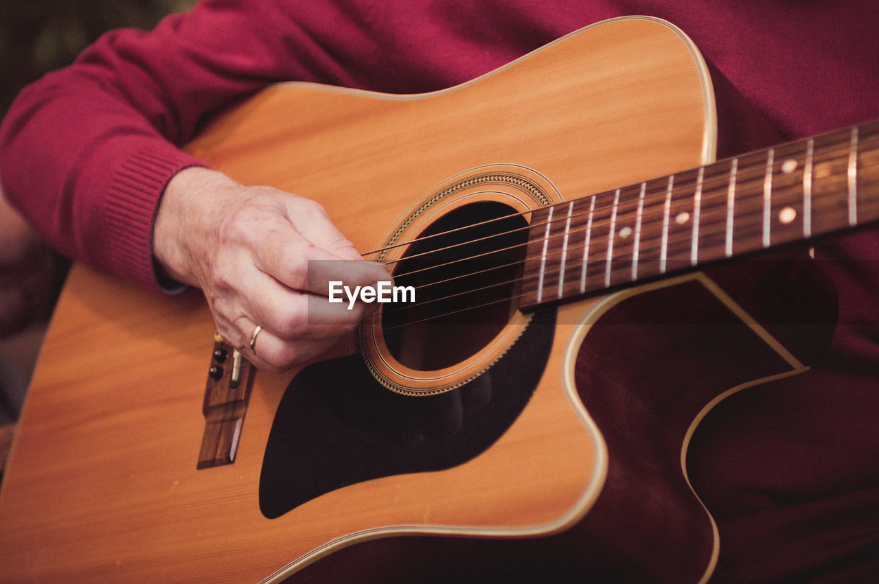 Midsection of man playing guitar