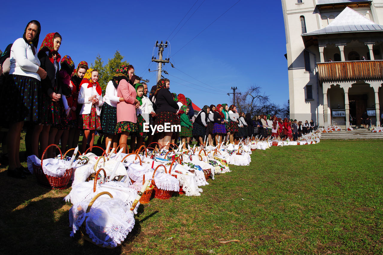 GROUP OF PEOPLE ON FIELD AGAINST BUILT STRUCTURES