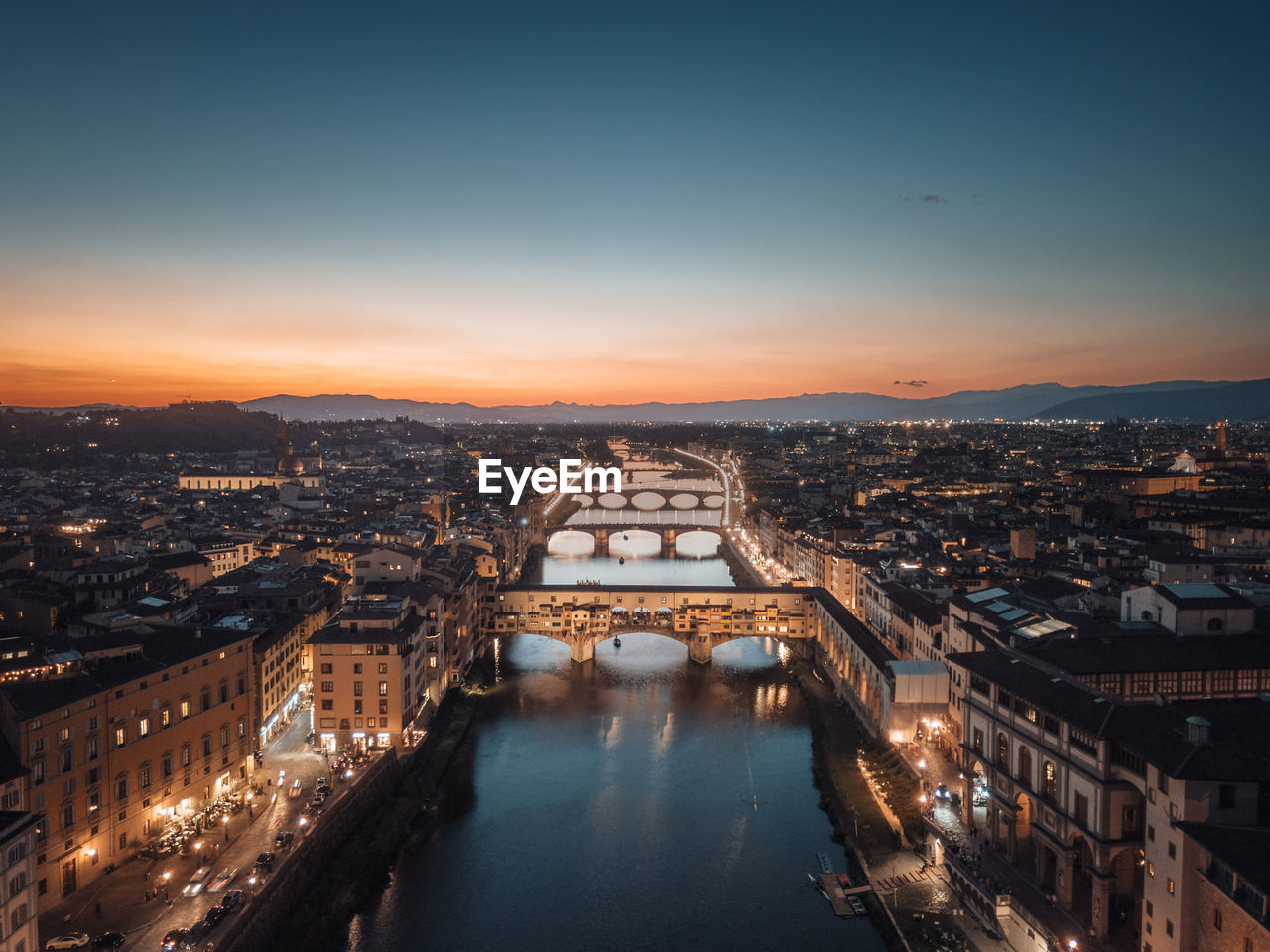 Aerial view of the illuminated city of florence at dusk with the arno river and the ponte vecchio