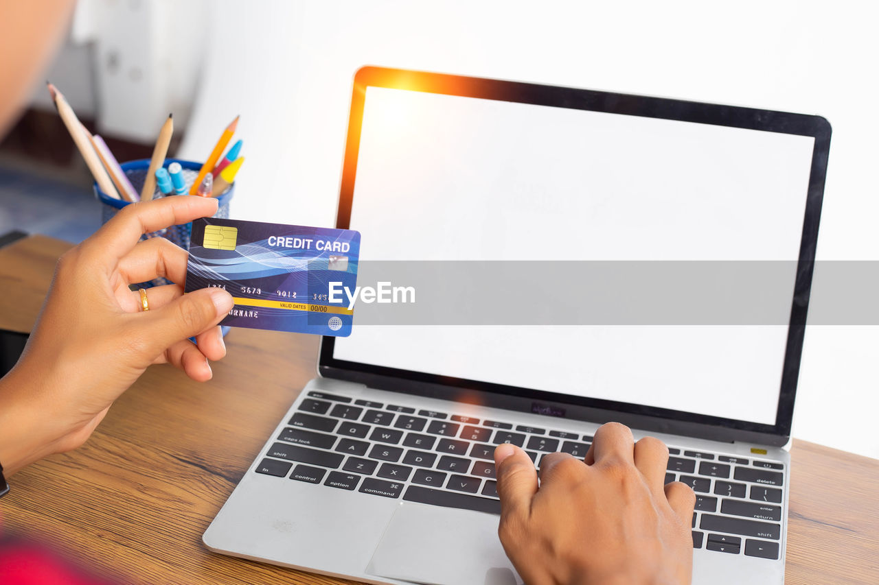 MIDSECTION OF WOMAN USING LAPTOP ON TABLE