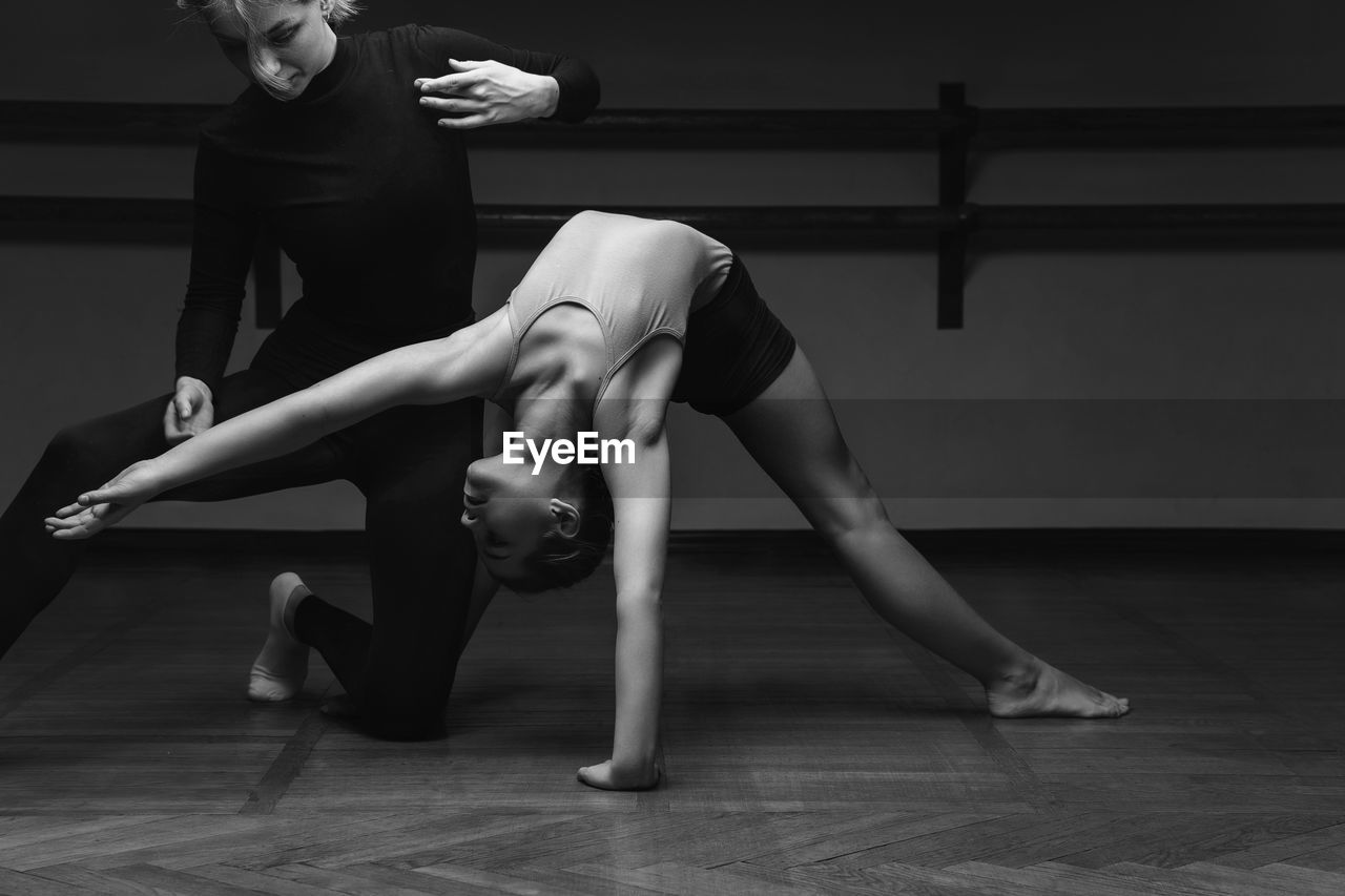 Portrait of a choreographer's teacher helping a little girl to pose correctlyin a dance studio