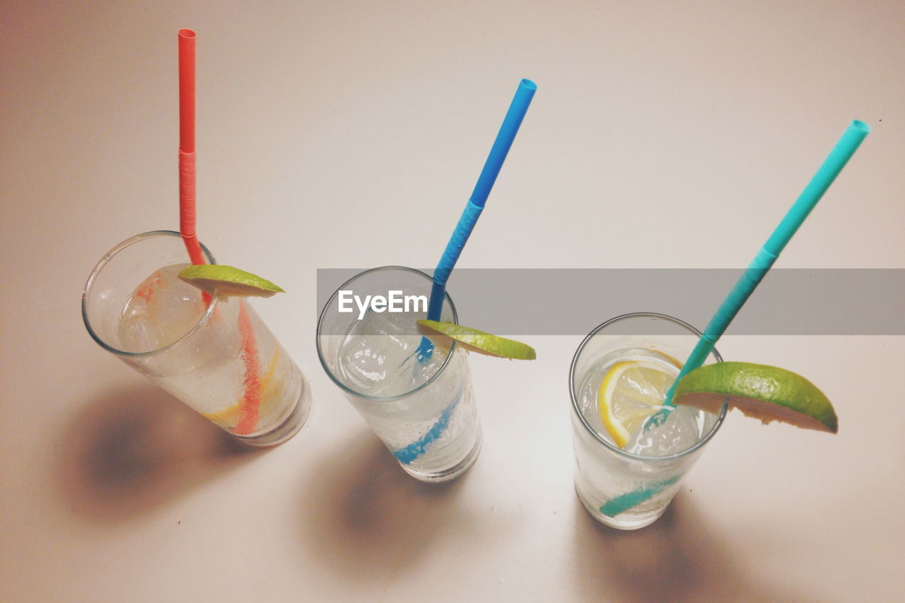 High angle view of highball cocktails with multi colored straws on table