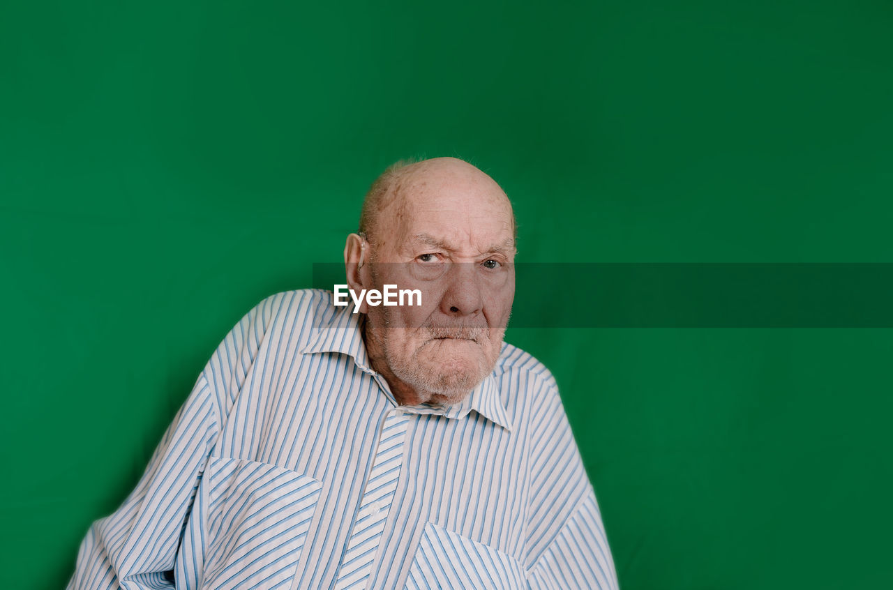 PORTRAIT OF MAN WEARING MASK AGAINST GREEN BACKGROUND