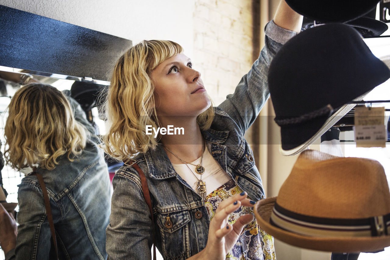 Woman choosing hat from stand in store