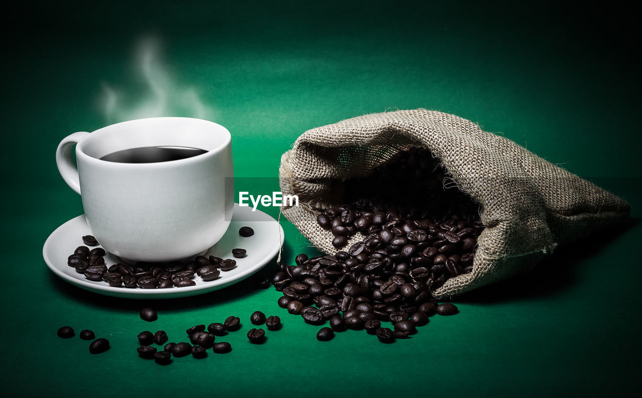 CLOSE-UP OF COFFEE CUP ON TABLE AGAINST BLACK BACKGROUND