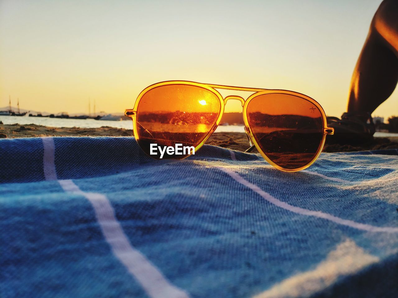 CLOSE-UP OF SUNGLASSES ON GLASS AT SUNSET