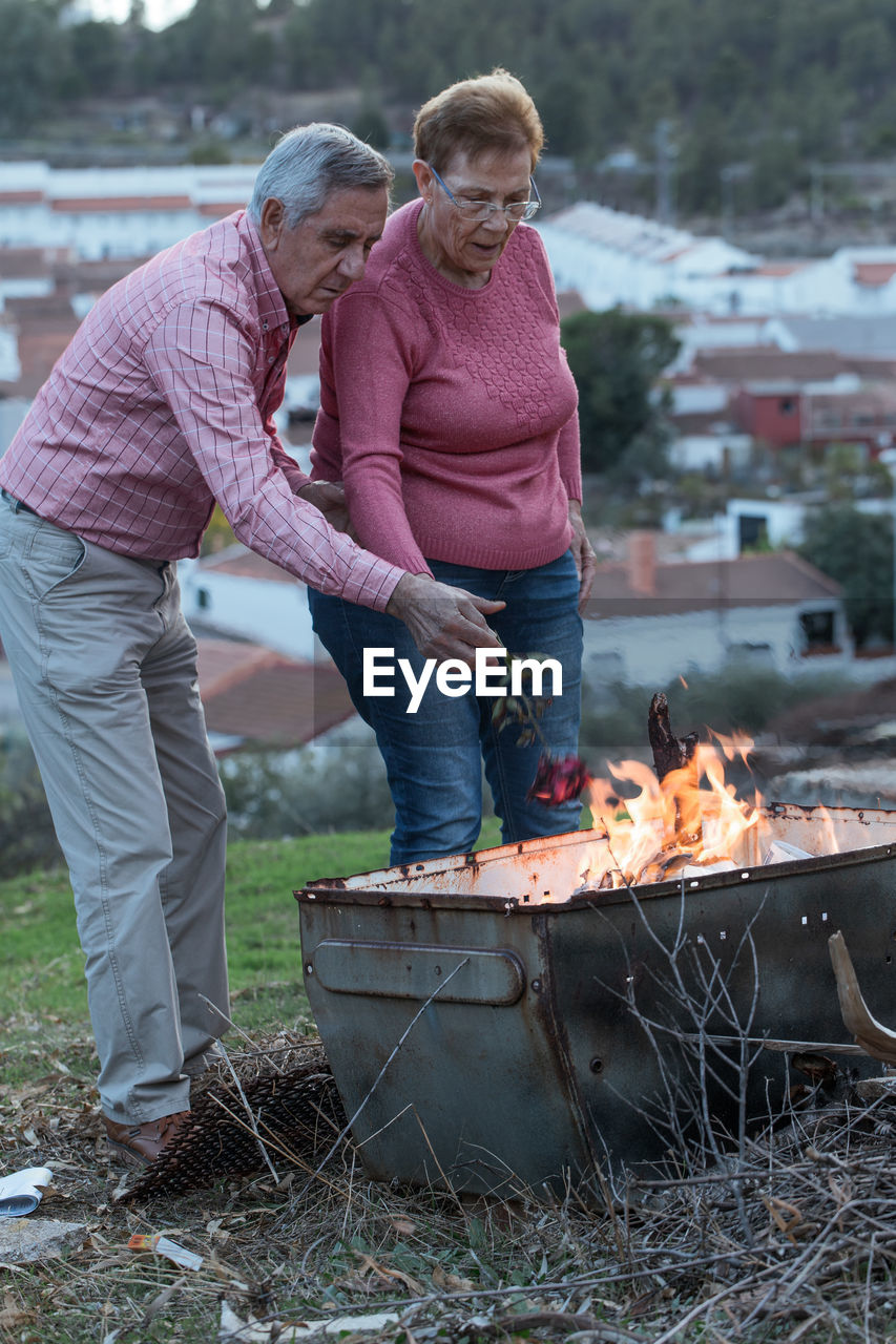 Senior couple burning rose standing outdoors