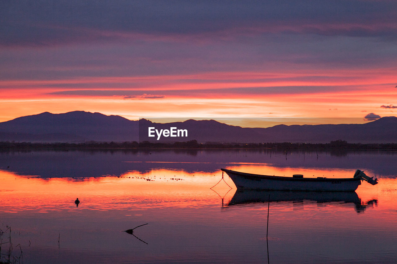 BOATS IN LAKE AGAINST ROMANTIC SKY AT SUNSET