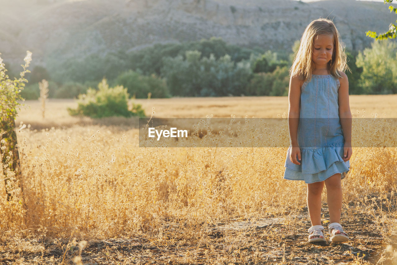 Full length of girl standing on grassy field against mountain