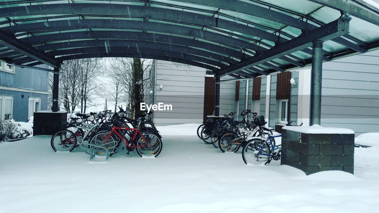 BICYCLE PARKED AGAINST SNOW COVERED BUILDINGS