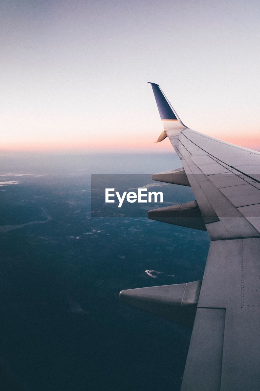 CROPPED IMAGE OF AIRPLANE WING OVER SEA