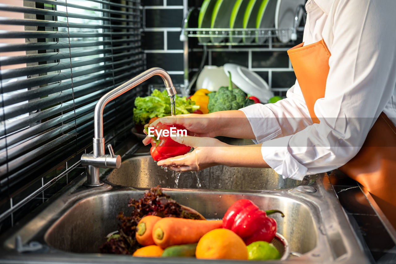 MIDSECTION OF MAN PREPARING FOOD AT KITCHEN