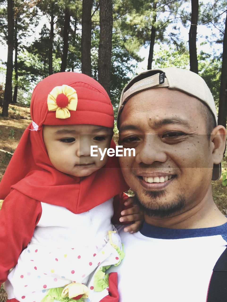 Portrait of smiling father and daughter standing against trees