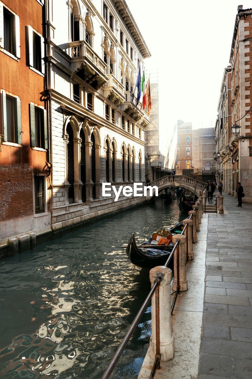 Building by canal against sky in city