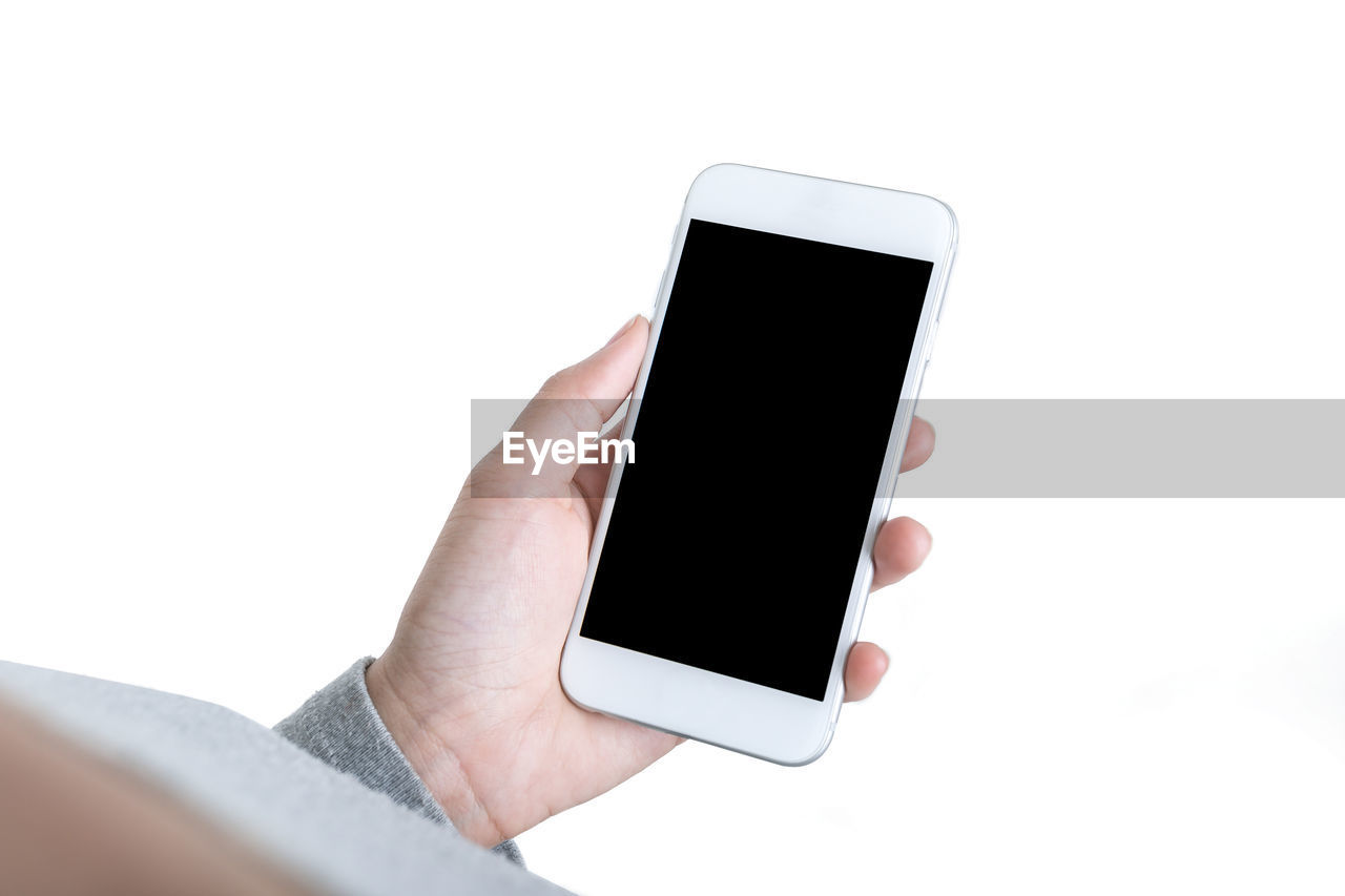 Cropped hand of person holding mobile phone against white background