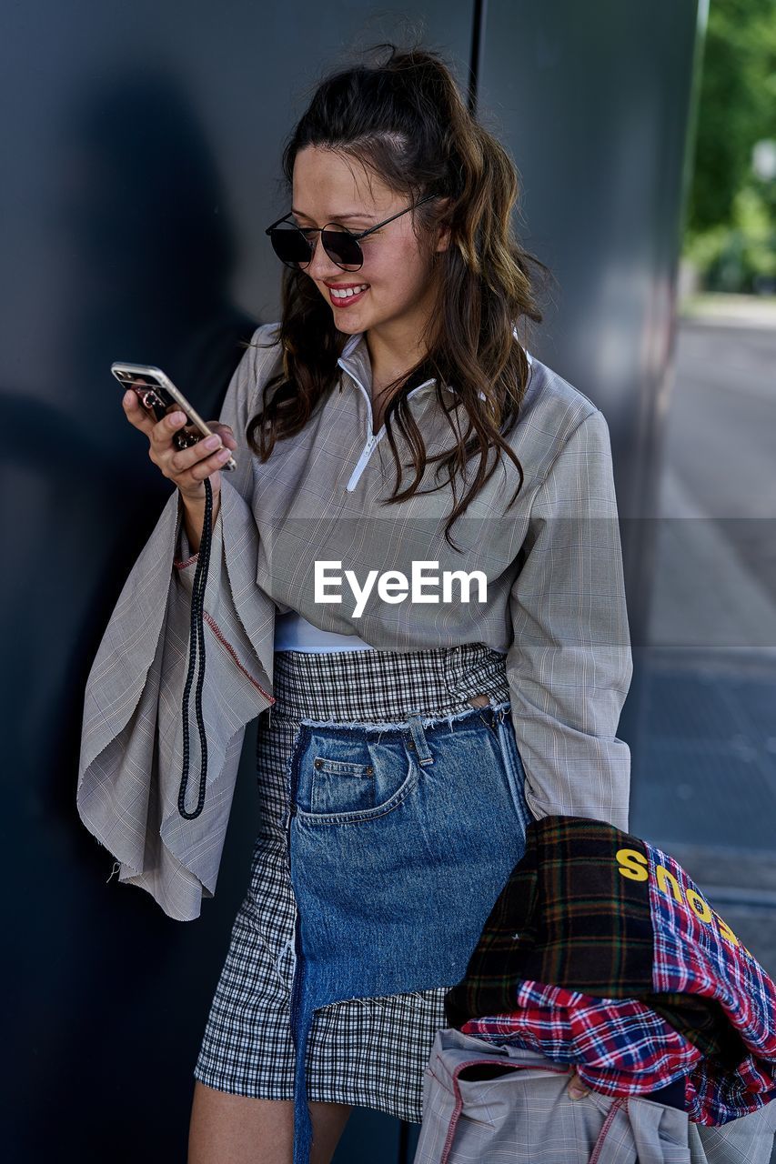 Young woman using mobile phone while standing outdoors