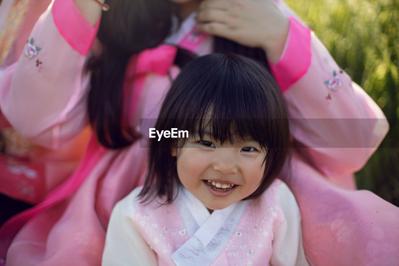 Korean national children pink costume on a four year old girl standing in a field with grass