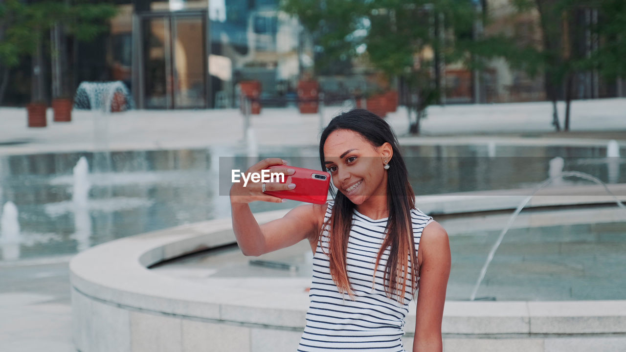 side view of young woman drinking water in city