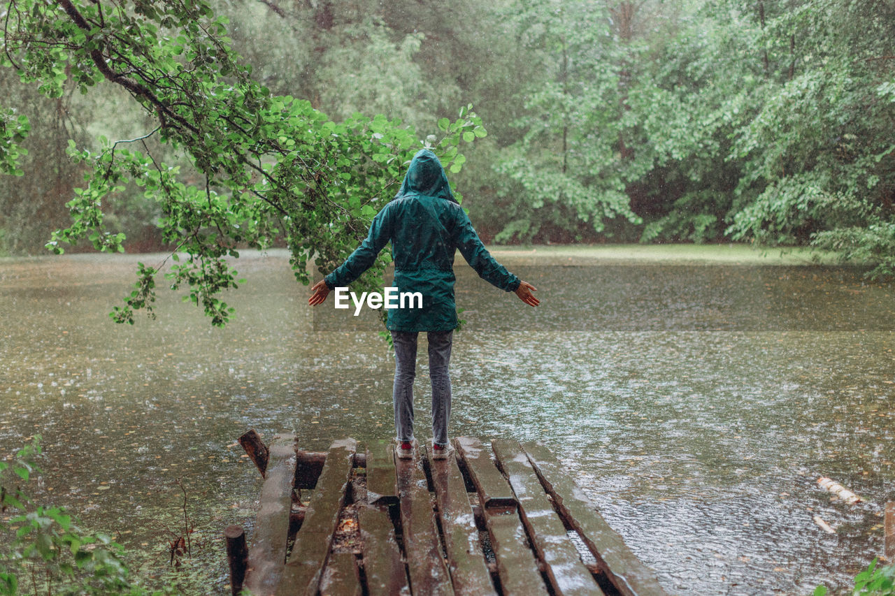 Rear view of girl standing on lake in forest