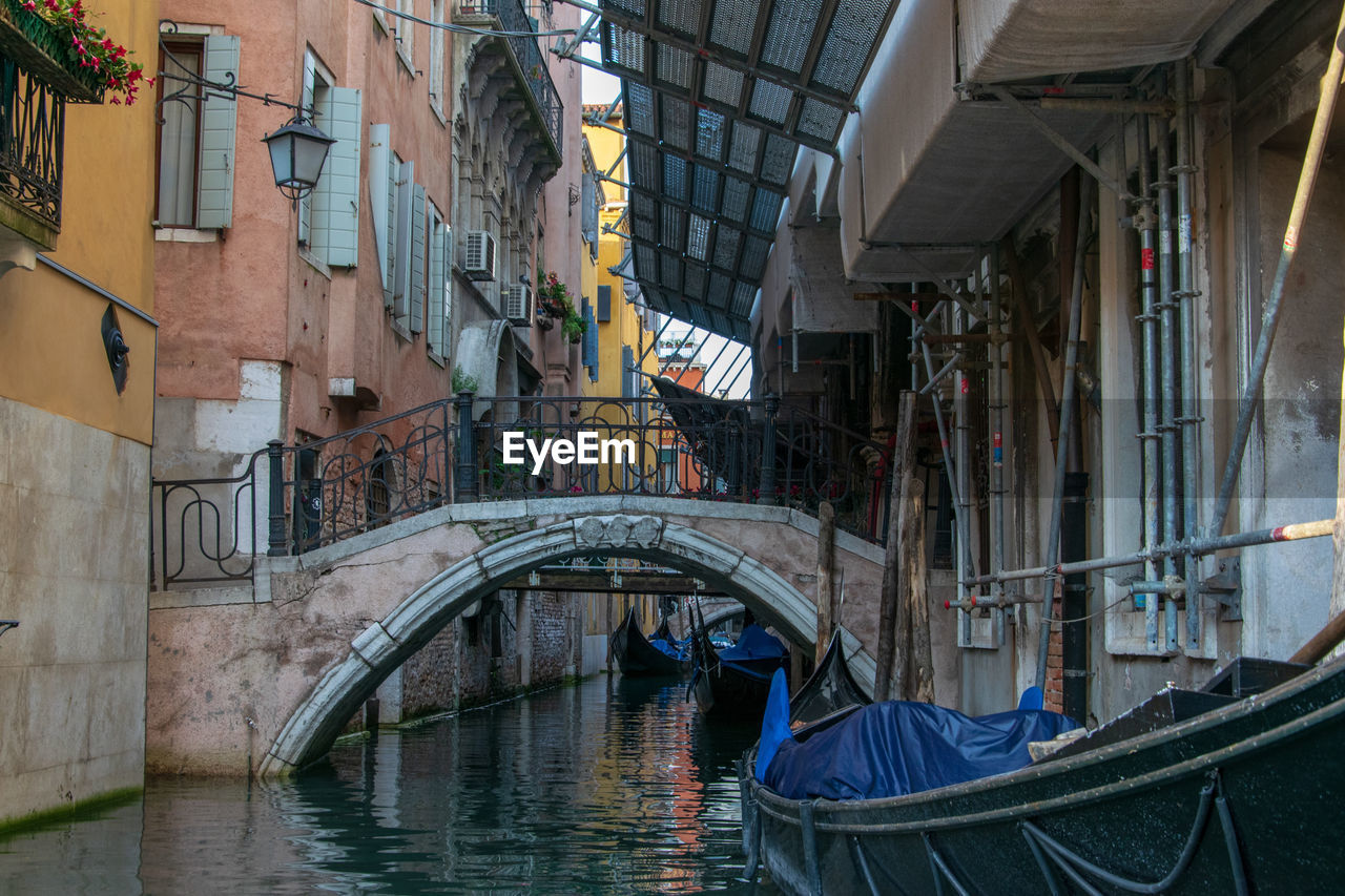 Arch bridge over canal amidst buildings in city