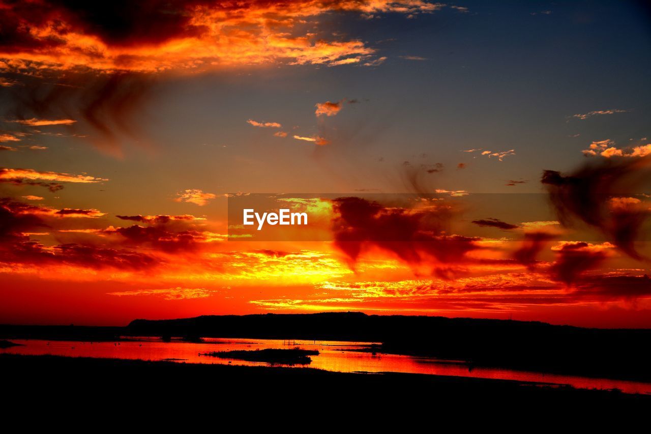 Scenic view of sea against dramatic sky during sunset