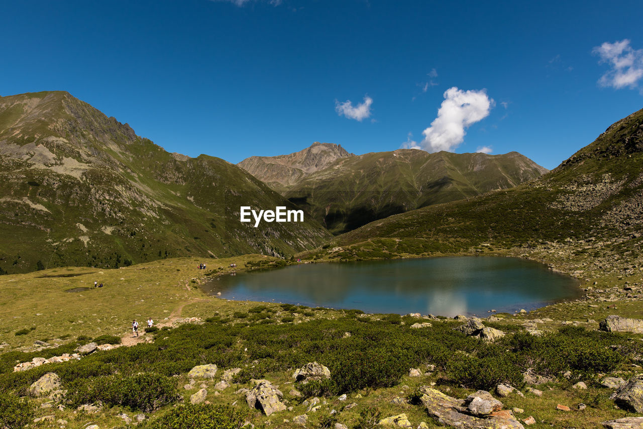 Scenic view of mountains by pond against sky