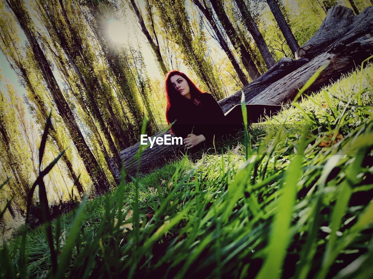 WOMAN SITTING ON GRASS IN FIELD