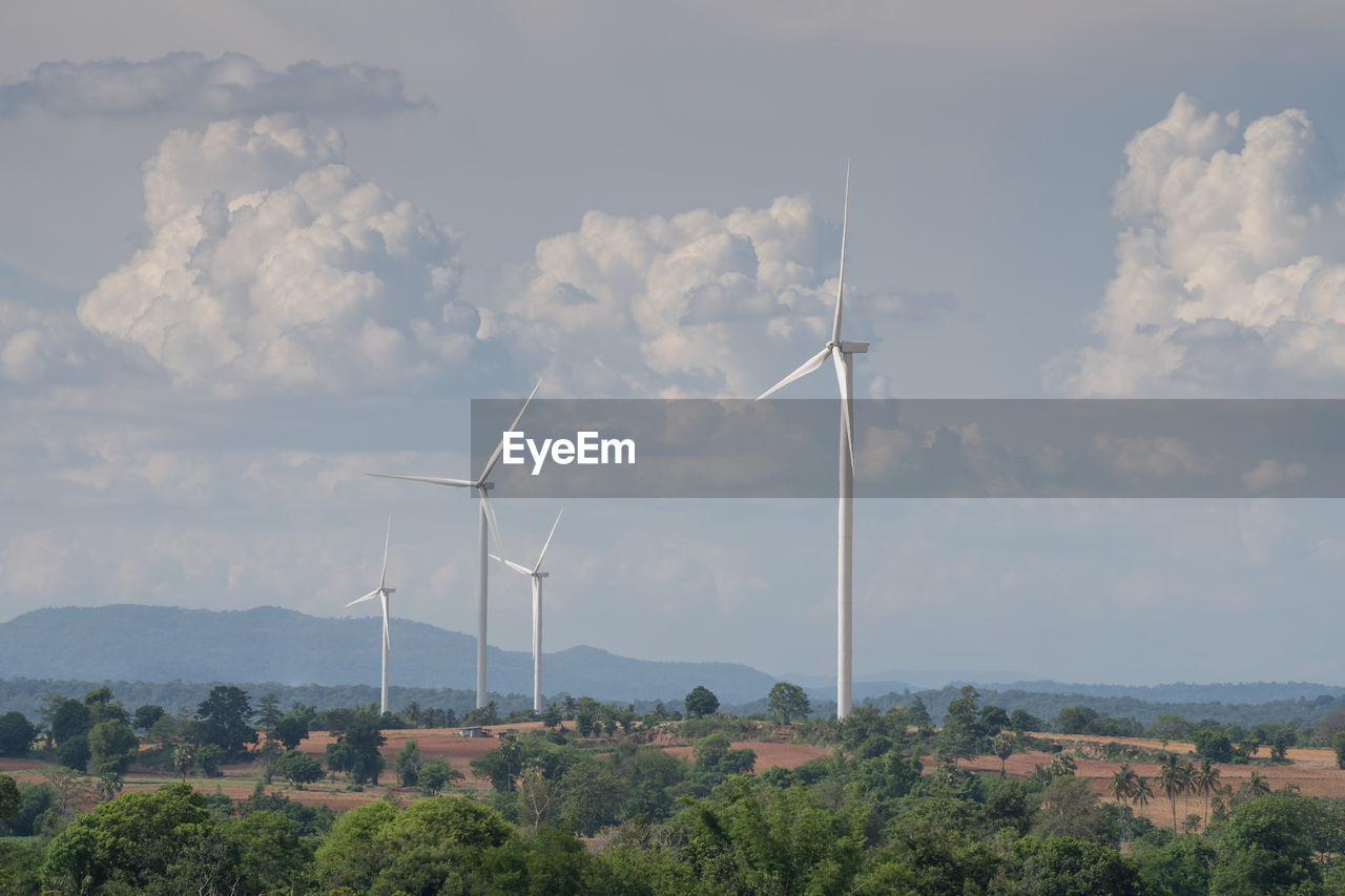 Wind turbines on field against sky