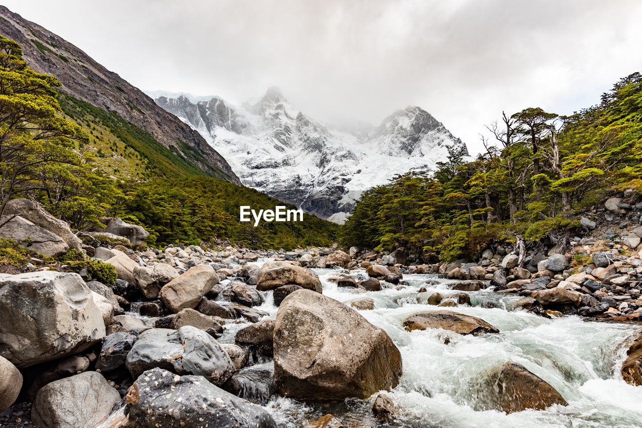 Scenic view of stream amidst rocks against sky