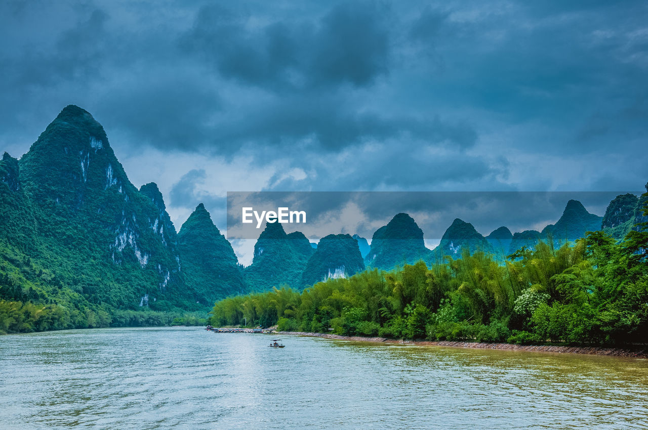 Scenic view of lake and mountains against dramatic sky