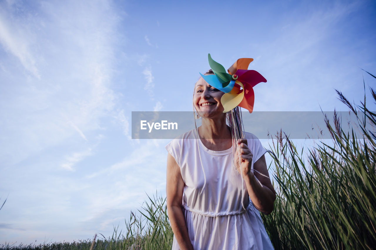 Girl with multicolored pigtails , face sideways, laughing, holding a windmill , wind energy