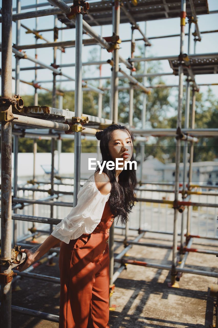 Portrait of young woman against scaffolding