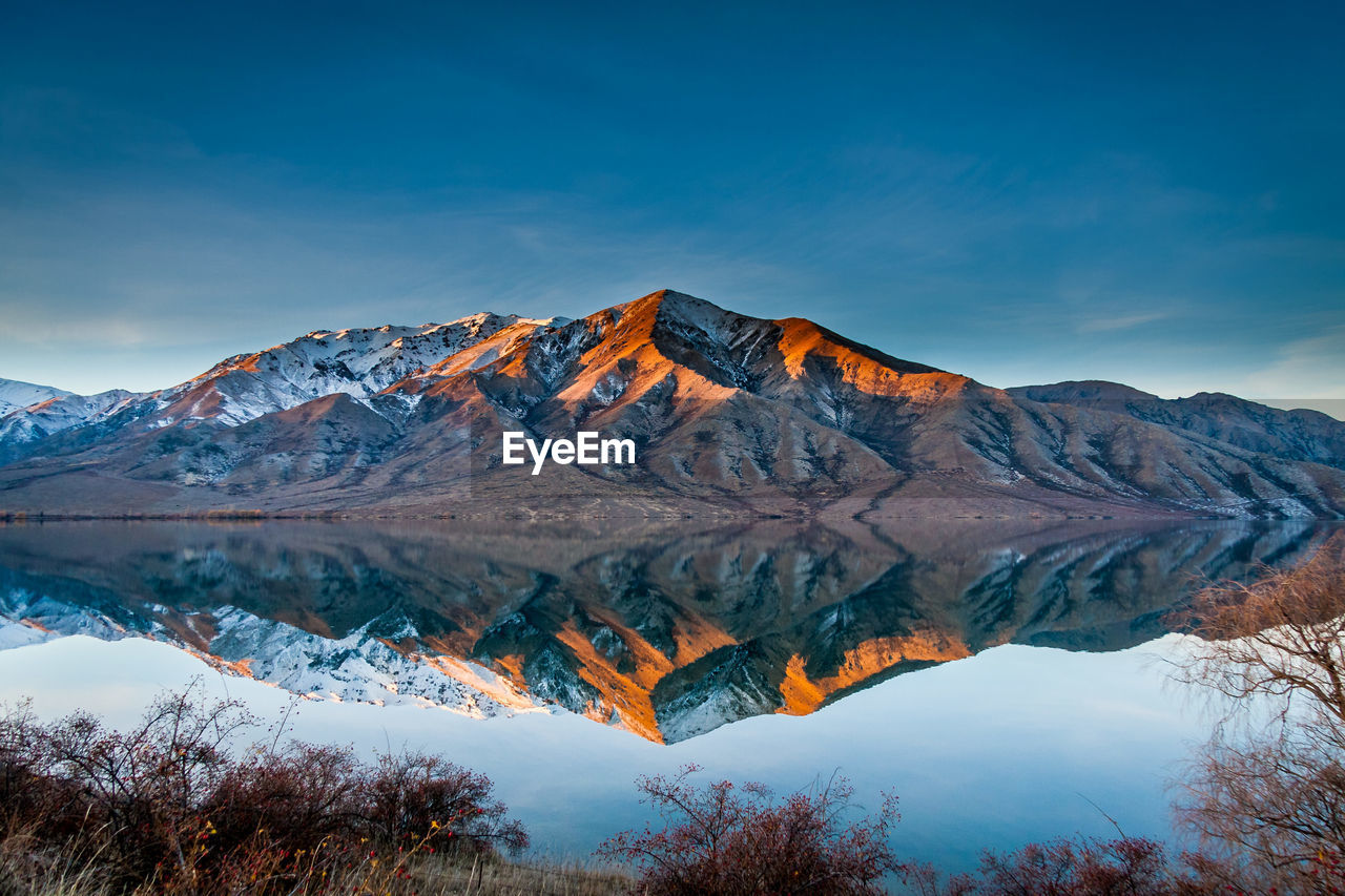 Reflection of mountain on lake against cloudy sky during sunset