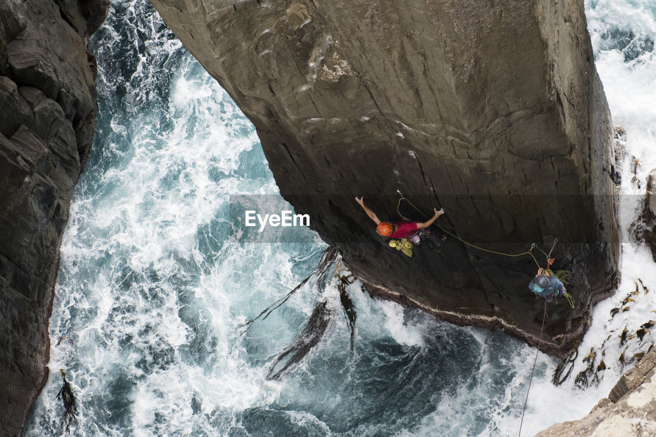 Rock climber climbs a pilar out of the ocean in tasmania, australia.