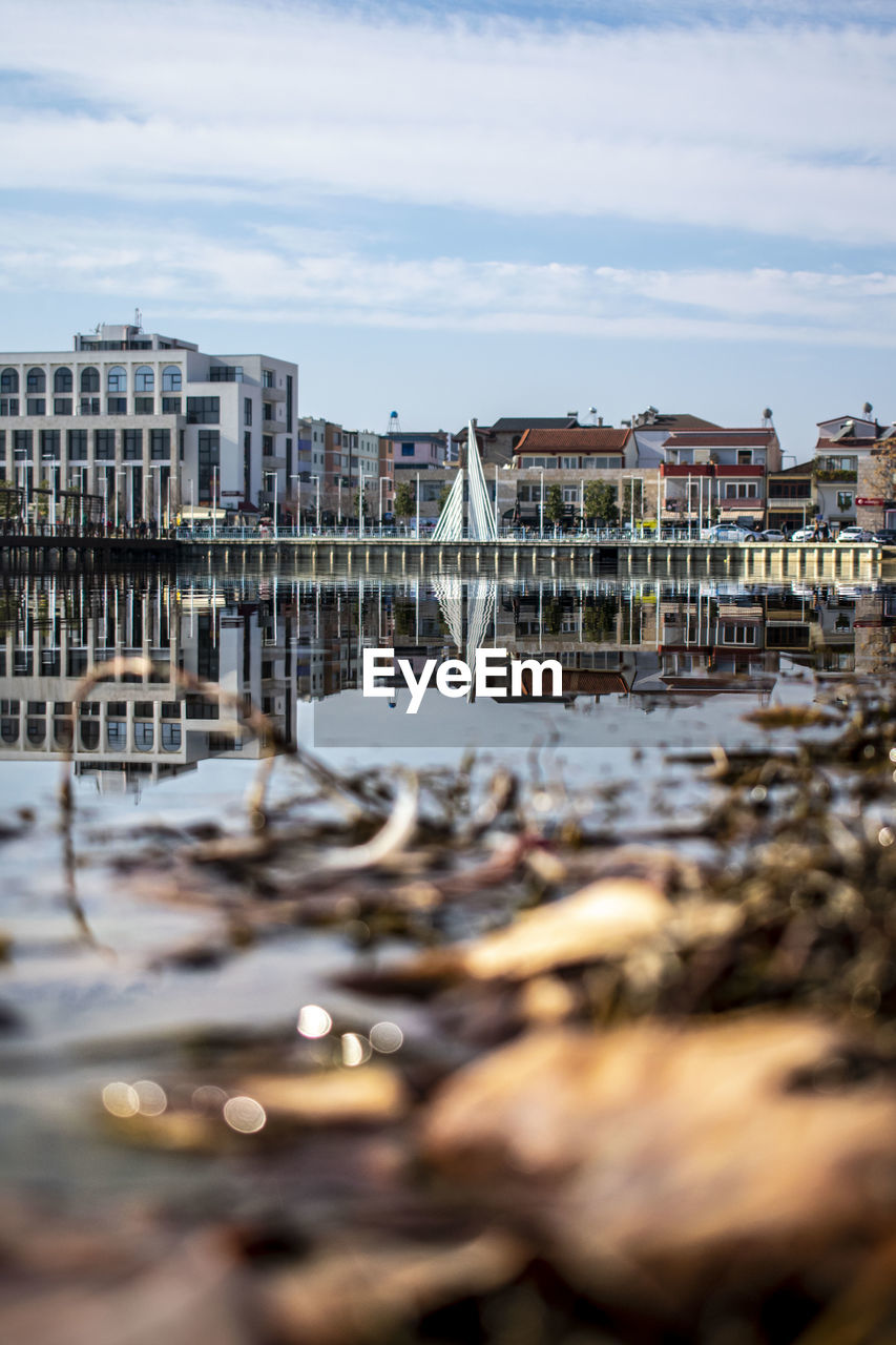 Buildings by river against sky in city