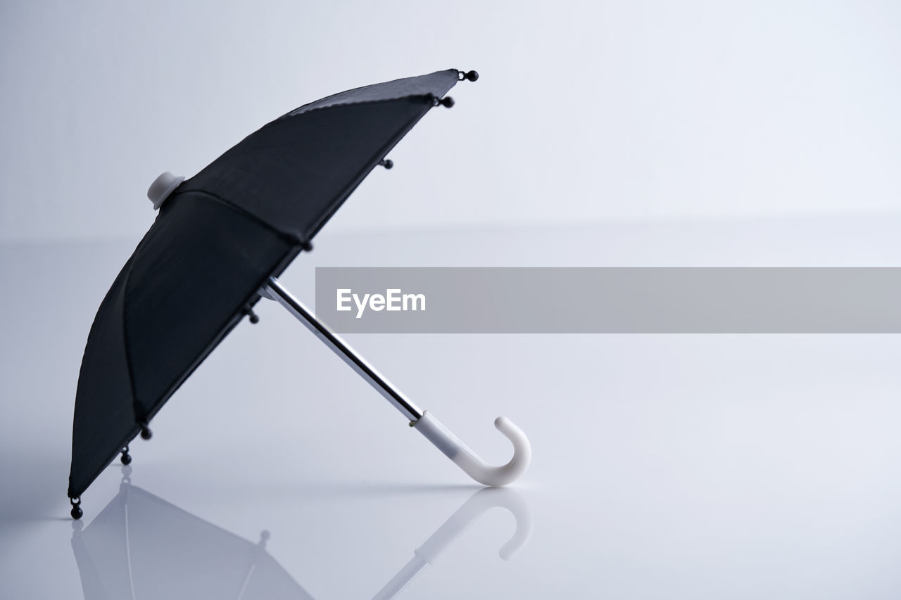 Small black umbrella on white background with reflection