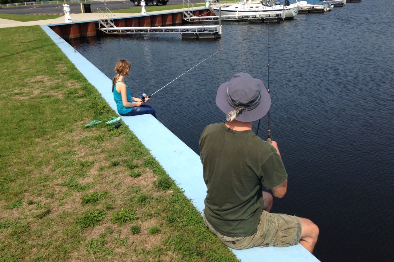 Man and girl fishing at lake