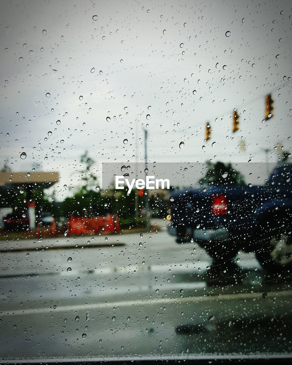 Road seen through wet glass window in rainy season