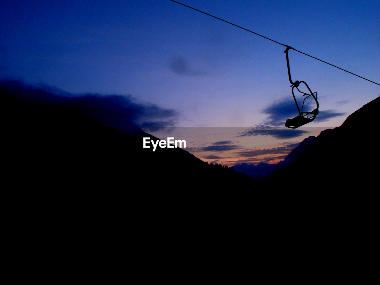 Low angle view of ski lift against sky during sunset