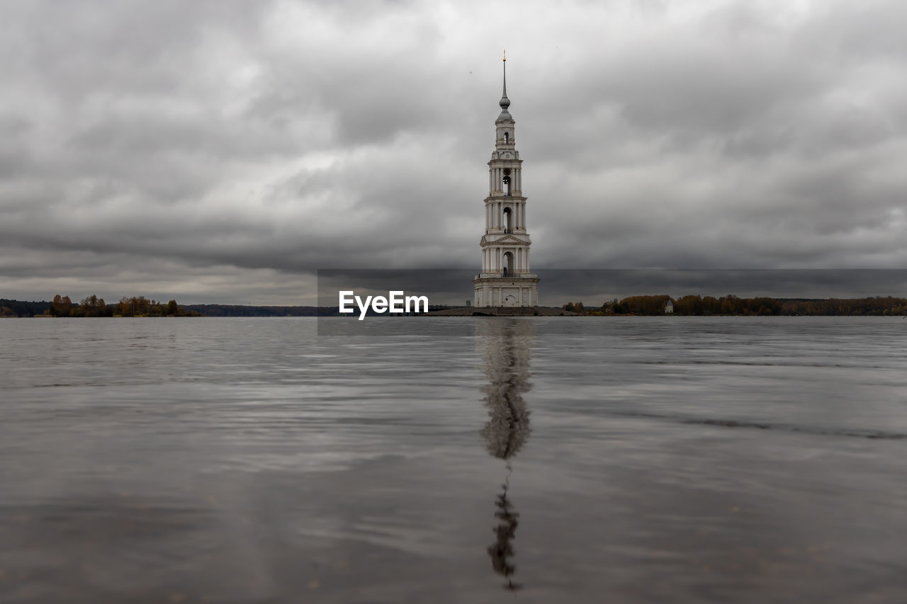 water, cloud, sky, reflection, architecture, tower, built structure, nature, travel destinations, sea, overcast, building, travel, no people, environment, storm, dramatic sky, building exterior, tourism, scenics - nature, landscape, outdoors, beauty in nature, horizon, storm cloud, day, land, history, tranquility, city, the past, religion, tranquil scene, atmospheric mood, beach, moody sky, shore