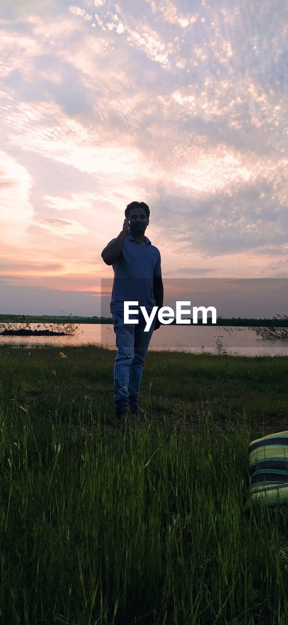 FULL LENGTH OF MAN STANDING ON FIELD AGAINST SKY