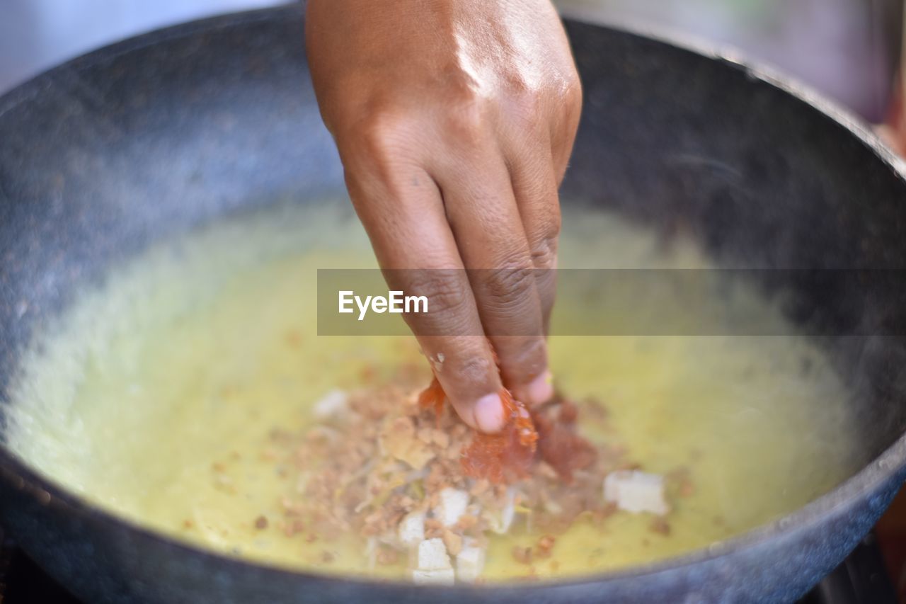 Cropped hand of man preparing food in bowl