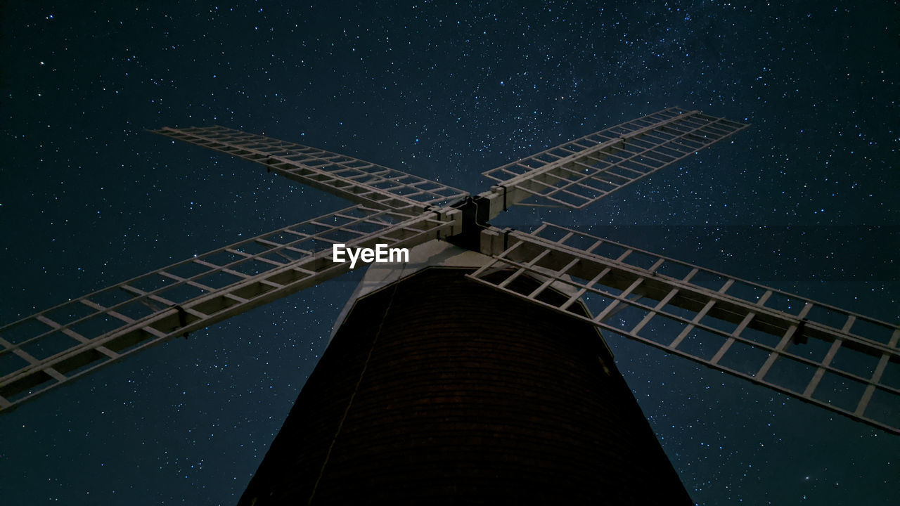 Low angle view of windmill against sky at night filled with stars