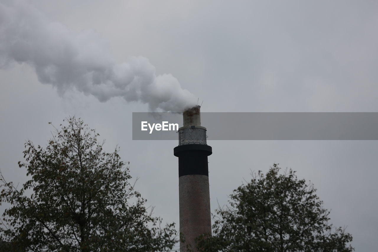 Low angle view of smoke emitting from chimney against sky