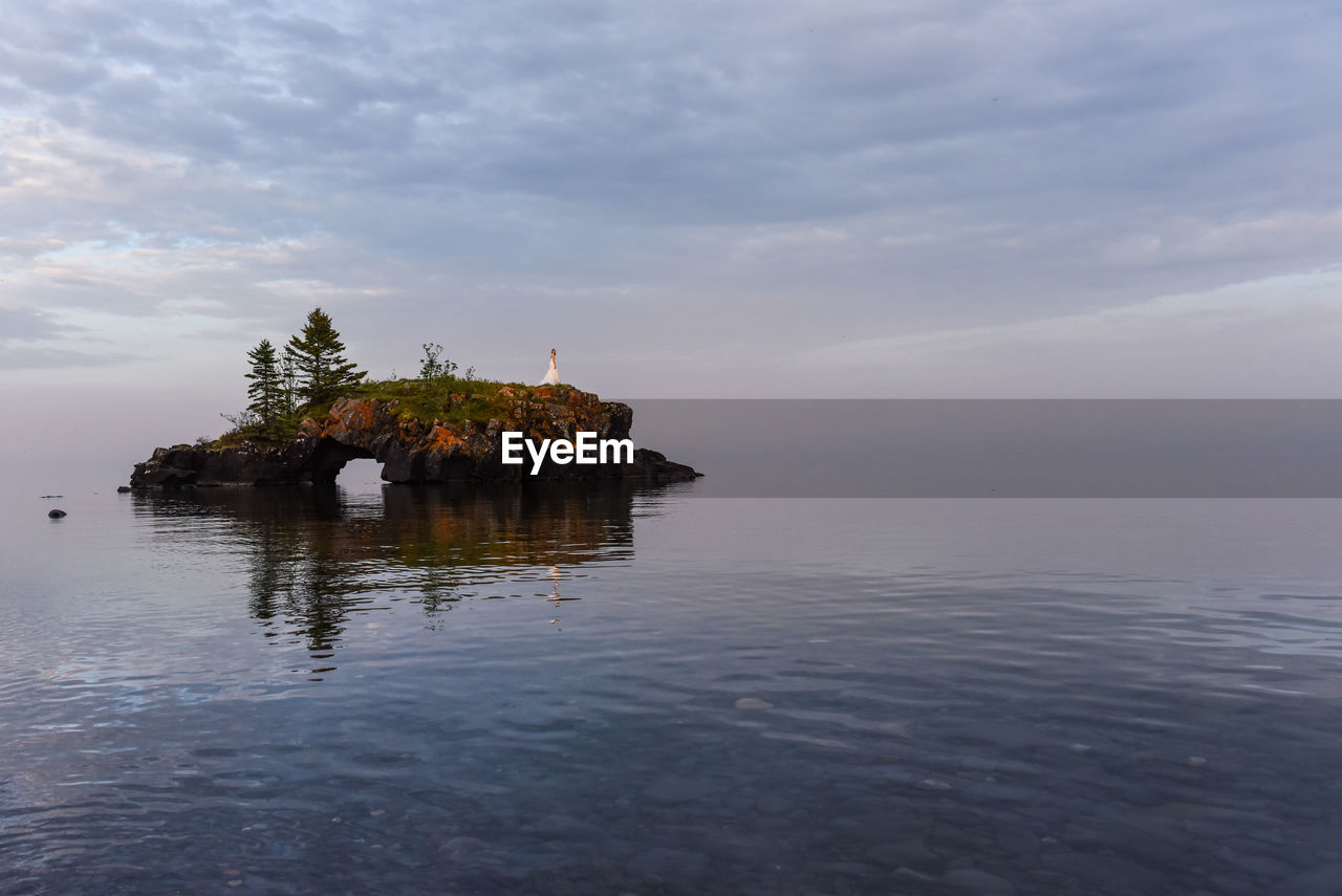 Island in sea against cloudy sky 
