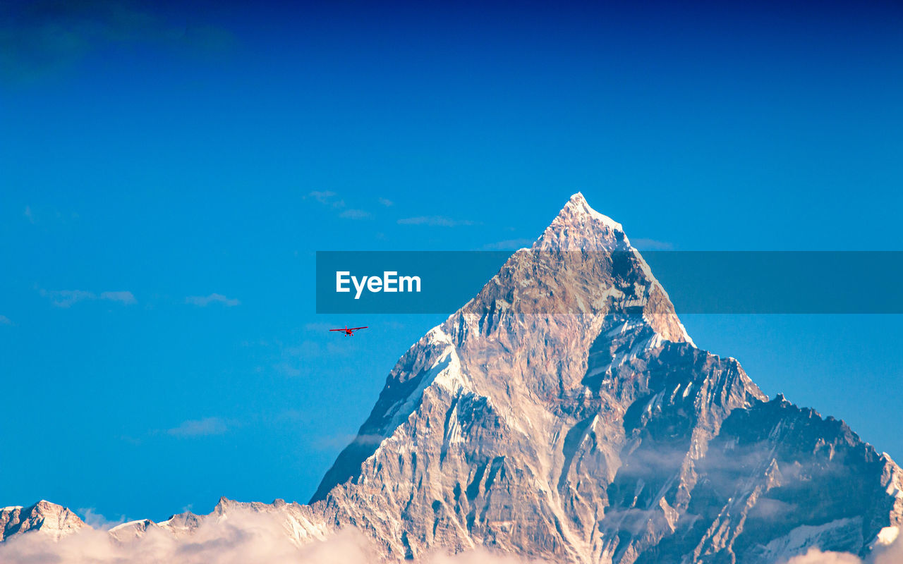 AERIAL VIEW OF SNOWCAPPED MOUNTAIN AGAINST BLUE SKY