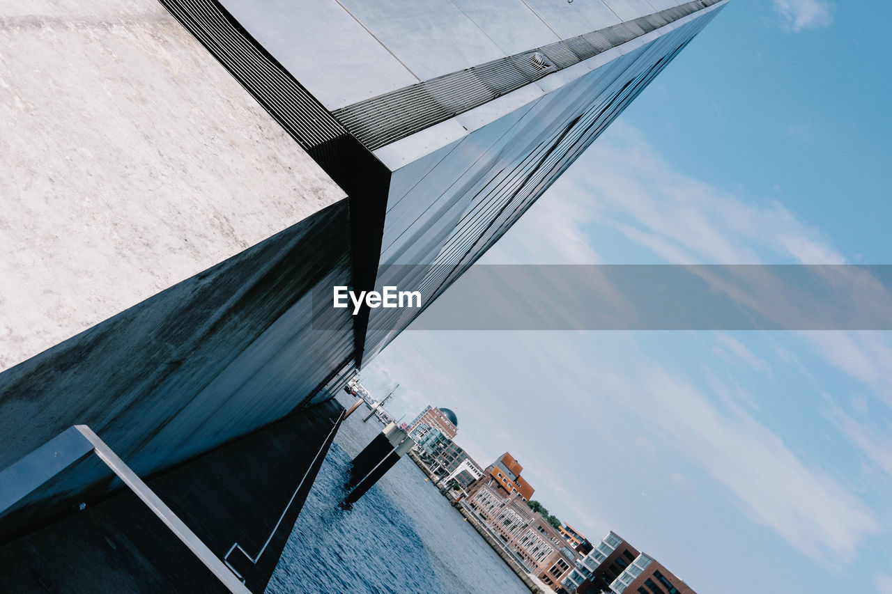 Tilt shot of buildings by river against sky