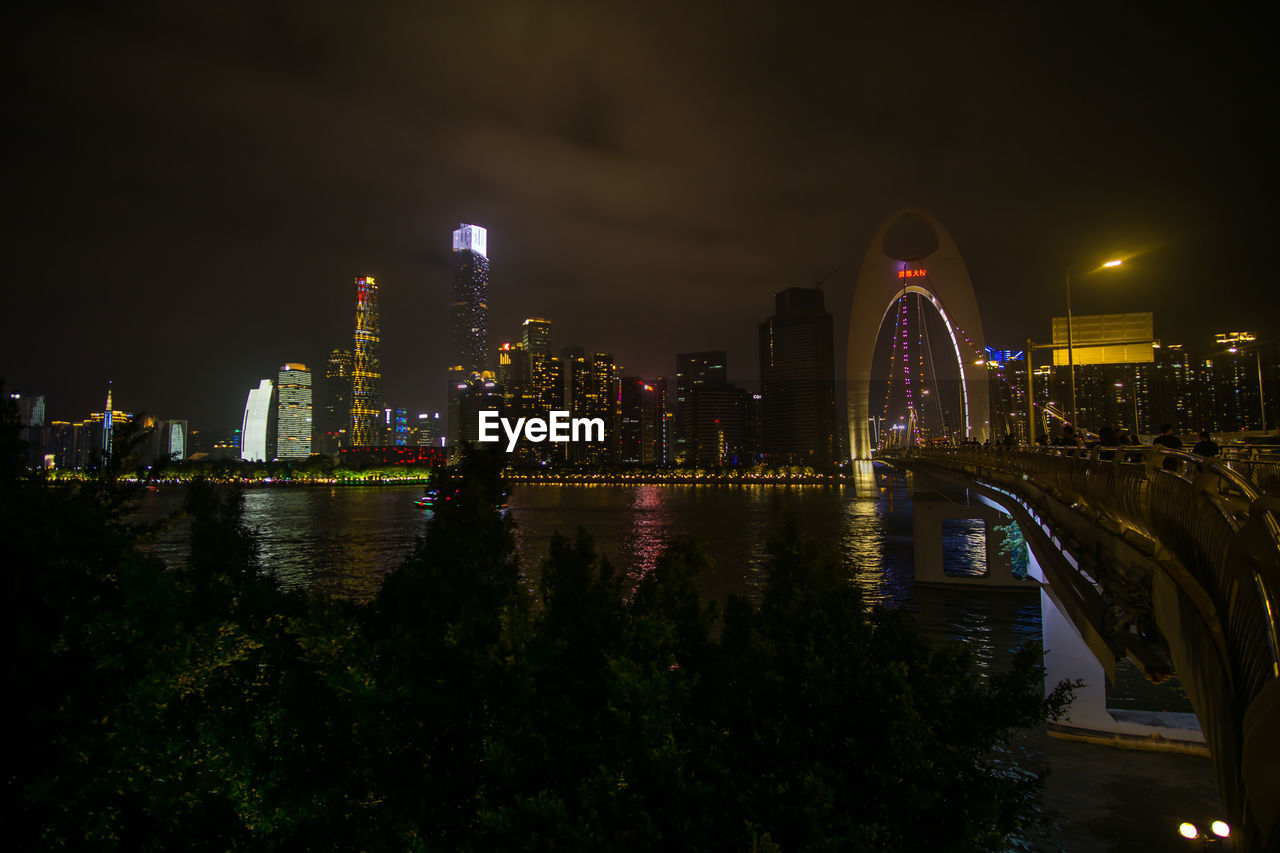 ILLUMINATED CITY BY RIVER AGAINST SKY