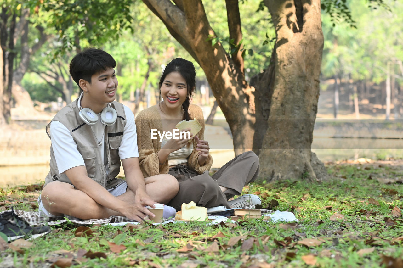side view of young woman using mobile phone while sitting on field