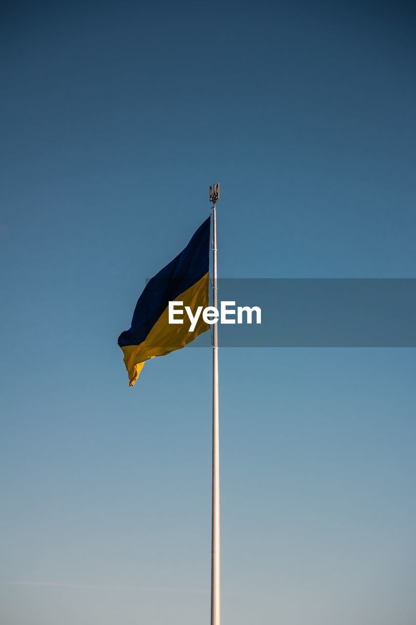 Low angle view of flag against clear blue sky